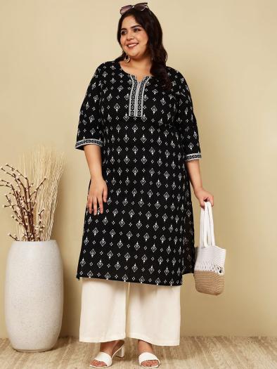 Preview: The model is wearing a long, black and white cotton tunic in size 3XL with wide-legged white summer trousers.